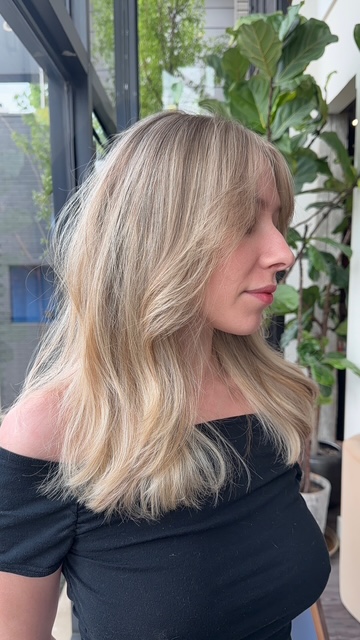 Blonde balayage with curtain bangs and layers by Evelyn